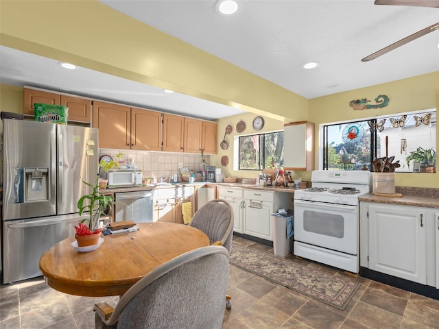 kitchen featuring appliances with stainless steel finishes, backsplash, dark tile patterned flooring, and ceiling fan