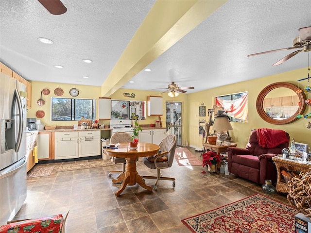 dining space featuring beamed ceiling, ceiling fan, light tile patterned flooring, and a textured ceiling