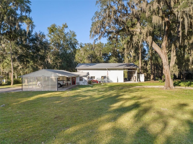 rear view of property with a pole building, an outbuilding, a carport, and a yard