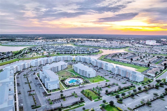 aerial view at dusk featuring a water view and a city view