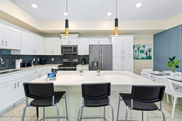 kitchen with decorative light fixtures, light countertops, appliances with stainless steel finishes, white cabinets, and a sink