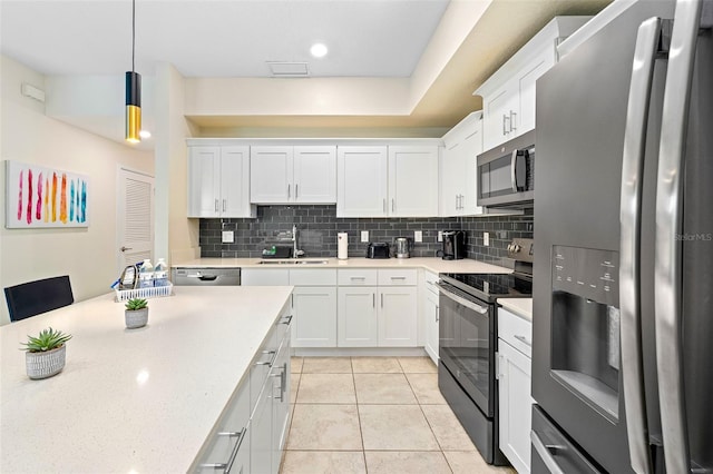 kitchen with stainless steel appliances, hanging light fixtures, a sink, and white cabinetry