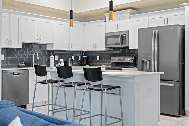 kitchen with appliances with stainless steel finishes, white cabinets, light countertops, and a kitchen breakfast bar