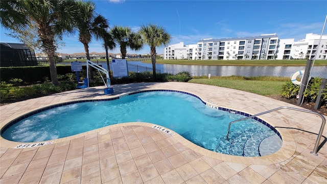 view of swimming pool featuring a patio area, a swimming pool, a water view, and fence