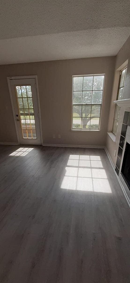 unfurnished living room with hardwood / wood-style flooring and a textured ceiling