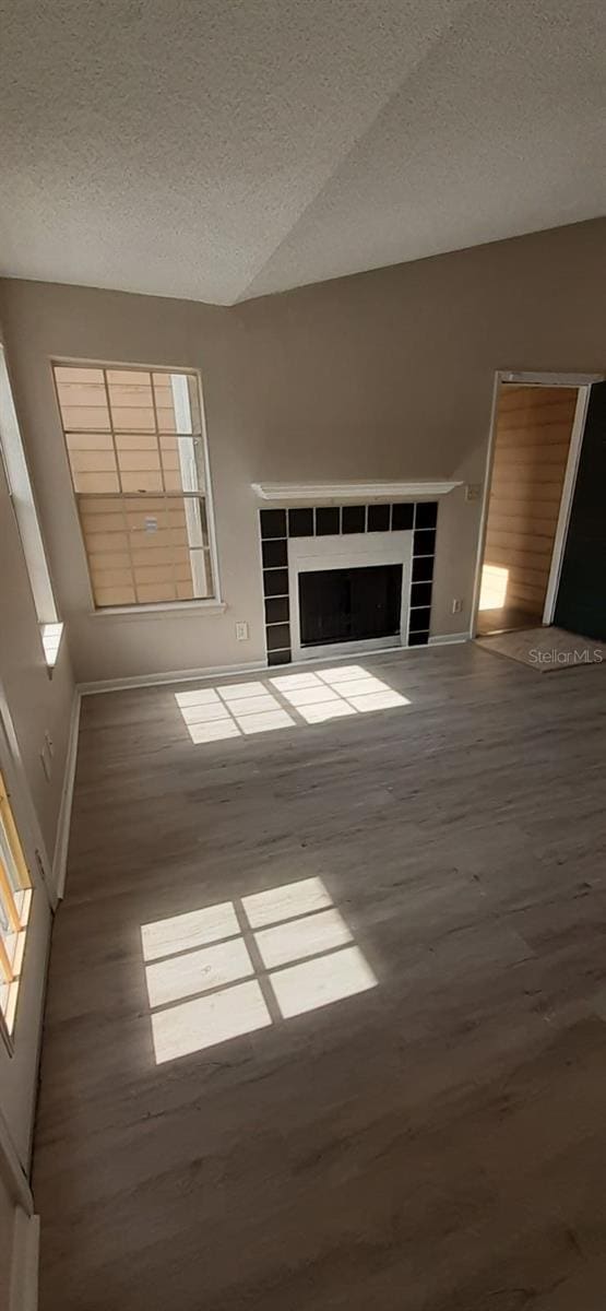 unfurnished living room with a fireplace, a textured ceiling, and hardwood / wood-style flooring