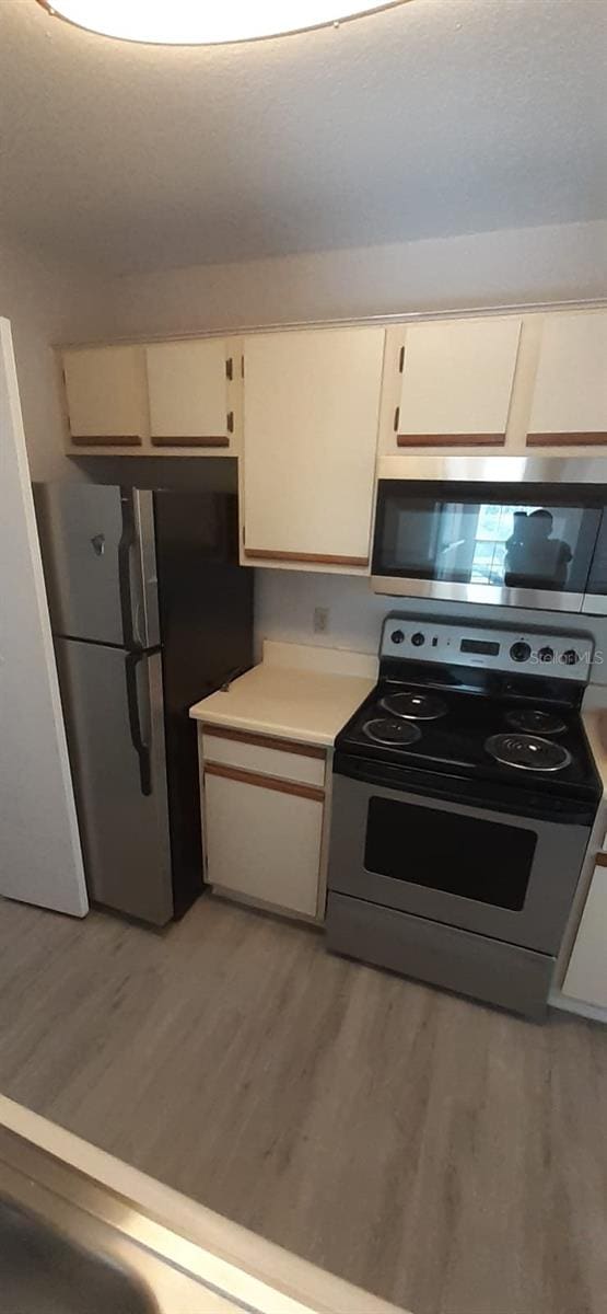 kitchen featuring white cabinets, light wood-type flooring, and appliances with stainless steel finishes