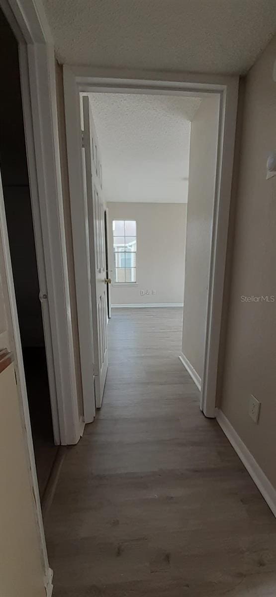 hall with light wood-type flooring and a textured ceiling