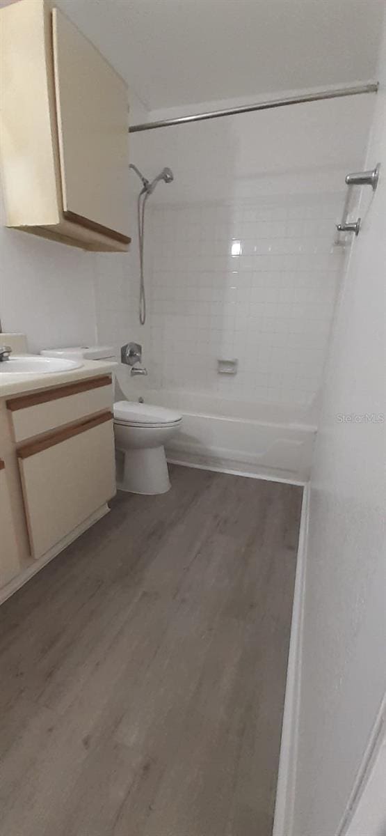 full bathroom with vanity, wood-type flooring, tiled shower / bath combo, and toilet