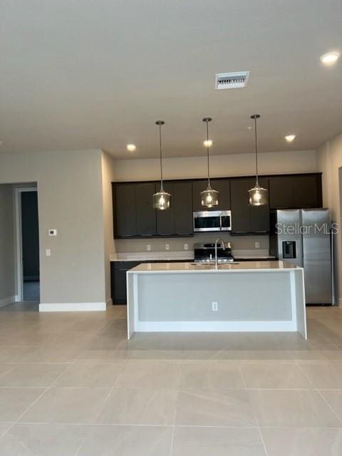 kitchen with pendant lighting, a center island with sink, appliances with stainless steel finishes, and light tile floors