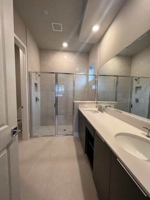 bathroom featuring tile floors, large vanity, double sink, and an enclosed shower