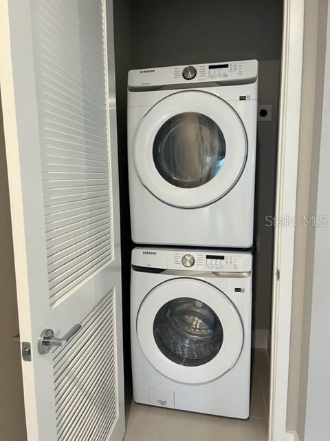 clothes washing area featuring stacked washer and clothes dryer