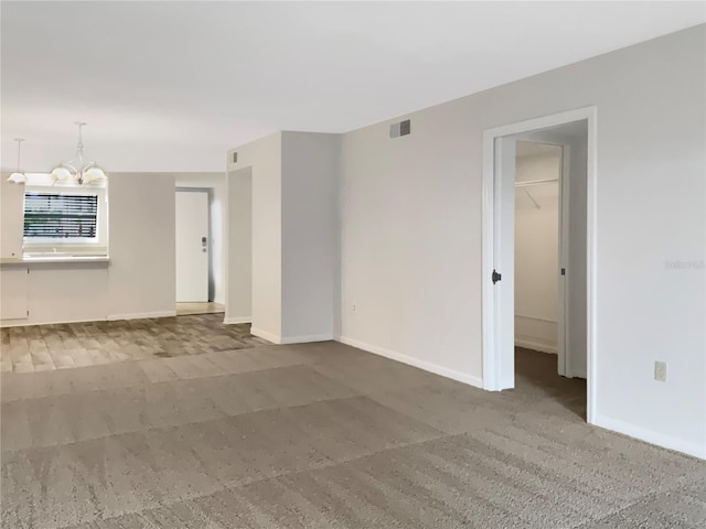 carpeted spare room featuring a chandelier