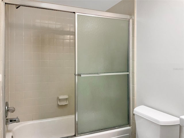 bathroom with toilet and combined bath / shower with glass door