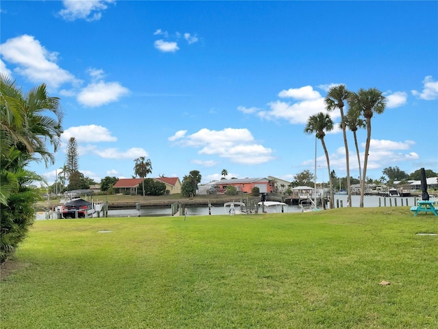 view of community with a water view, a yard, and a dock