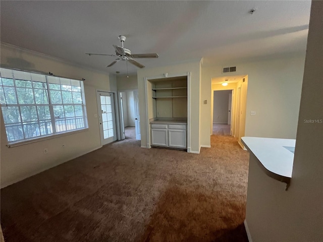 unfurnished living room featuring built in shelves, light carpet, and ceiling fan