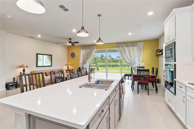 kitchen with white cabinets, appliances with stainless steel finishes, a center island with sink, and pendant lighting