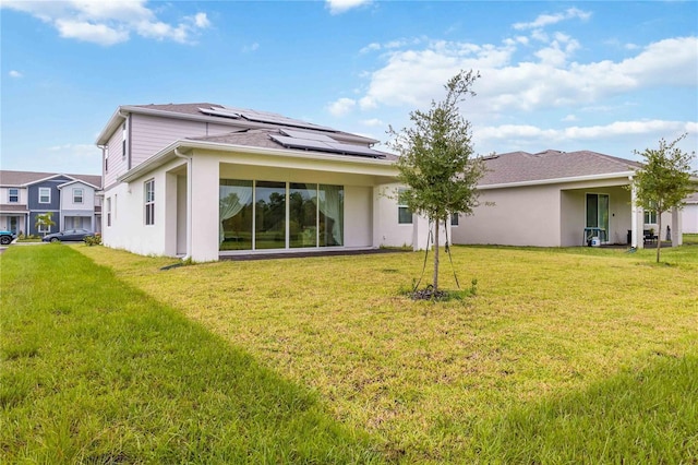 rear view of property featuring solar panels and a yard