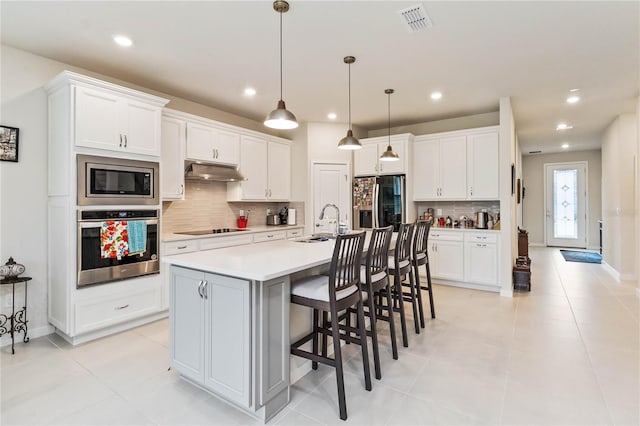 kitchen with hanging light fixtures, white cabinetry, a kitchen island with sink, and appliances with stainless steel finishes