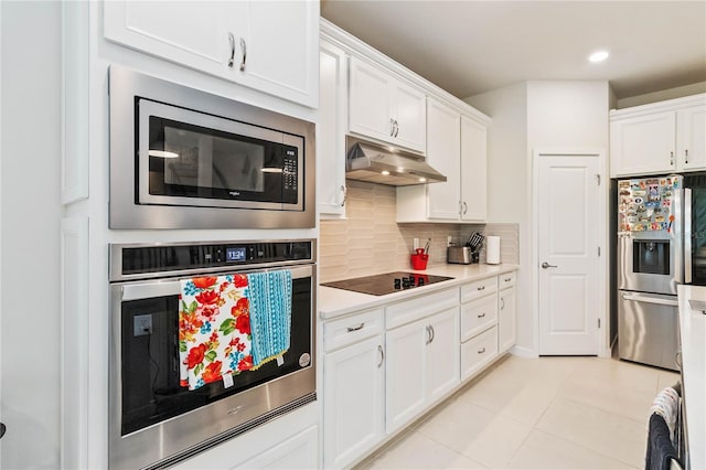 kitchen with light tile patterned floors, stainless steel appliances, white cabinetry, and tasteful backsplash