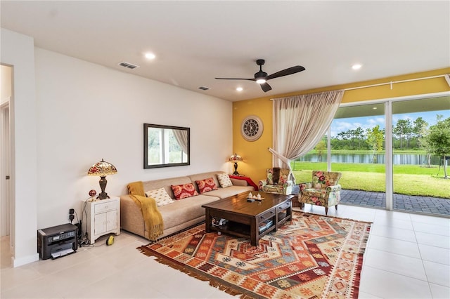 living room featuring ceiling fan, a water view, and light tile patterned floors