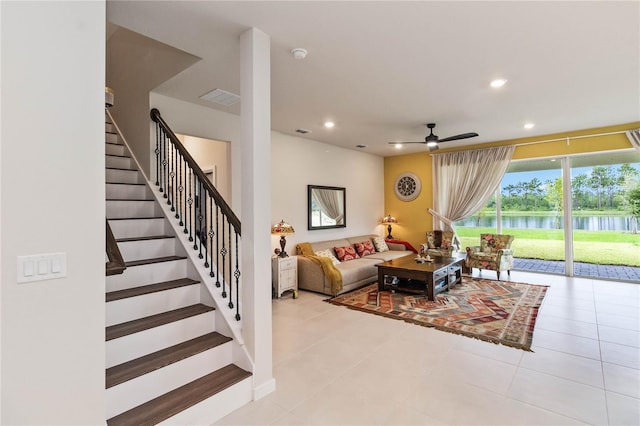 tiled living room with a water view and ceiling fan