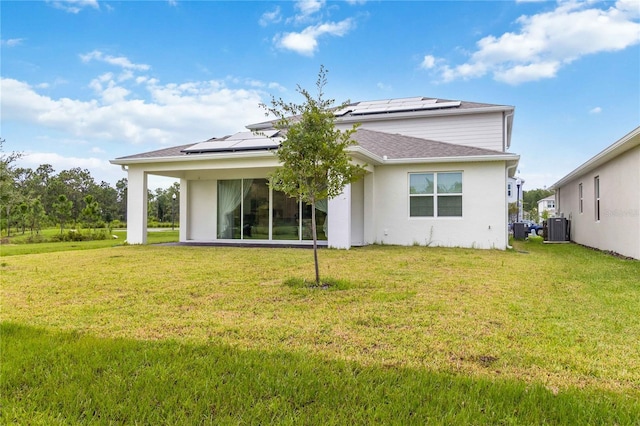 rear view of property featuring solar panels, cooling unit, and a lawn