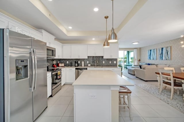 kitchen featuring light tile patterned floors, decorative light fixtures, decorative backsplash, white cabinetry, and stainless steel appliances