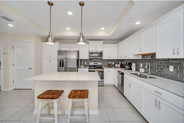 kitchen with light tile patterned flooring, sink, a center island, decorative backsplash, and stainless steel appliances