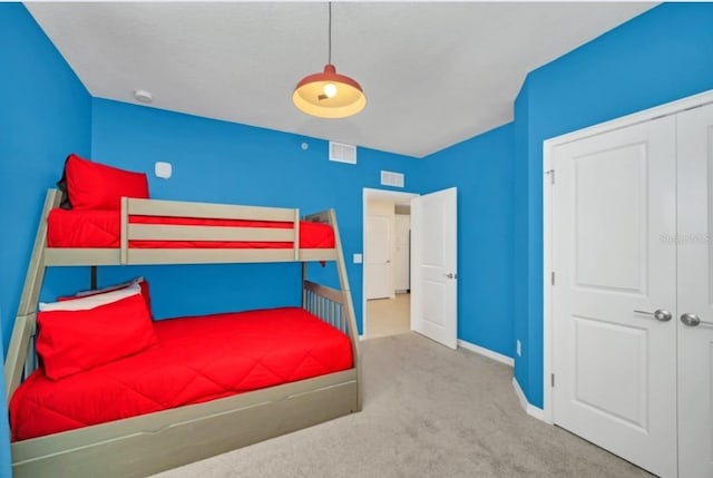 carpeted bedroom with visible vents, baseboards, and a closet