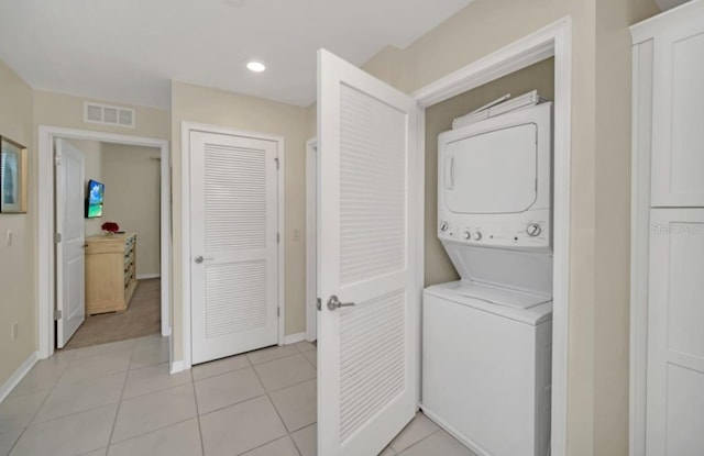 laundry room with stacked washing maching and dryer and light tile patterned floors