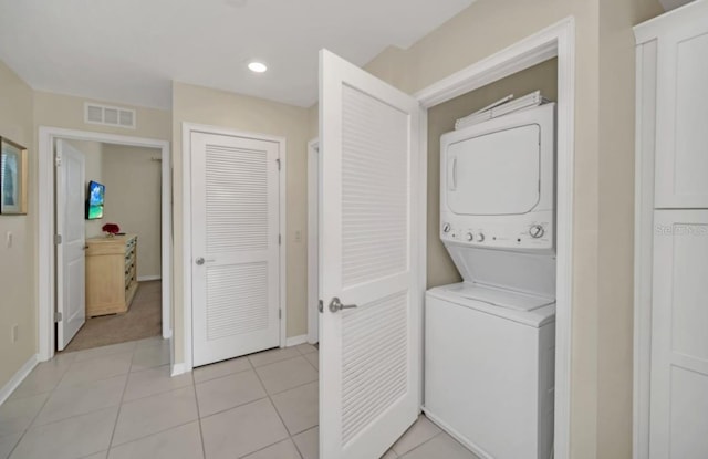 washroom featuring baseboards, visible vents, stacked washer and clothes dryer, and laundry area