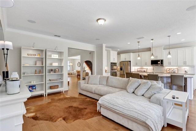 living room with crown molding, visible vents, wood finished floors, and recessed lighting