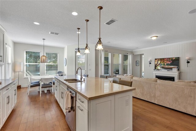 kitchen with hanging light fixtures, visible vents, white cabinets, and a sink