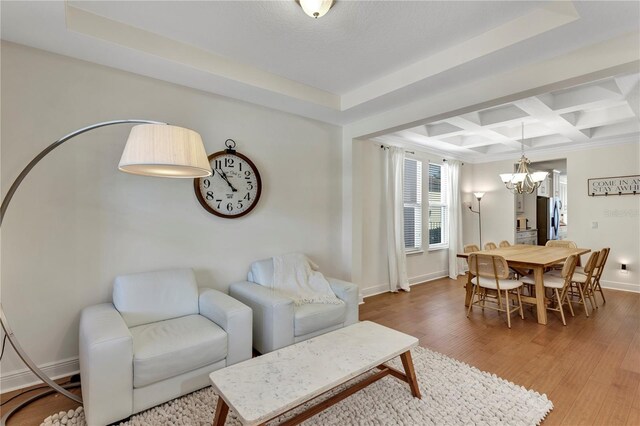 living area featuring an inviting chandelier, wood finished floors, coffered ceiling, beamed ceiling, and baseboards