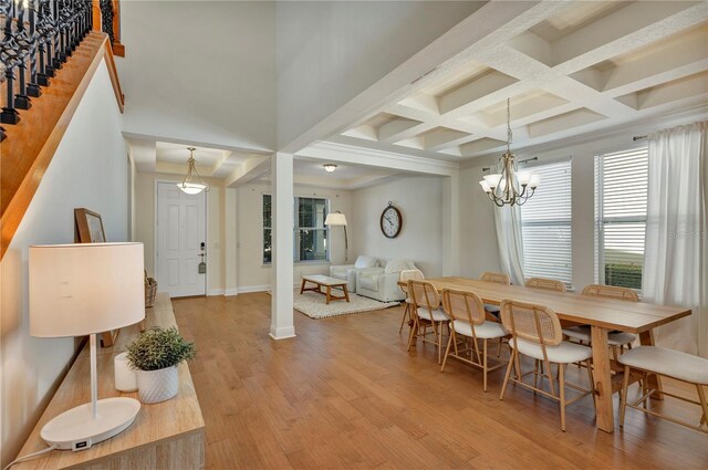 dining space with a notable chandelier, stairway, light wood-style floors, coffered ceiling, and baseboards