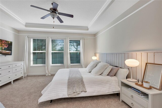 bedroom with a raised ceiling, light colored carpet, ceiling fan, and a textured ceiling