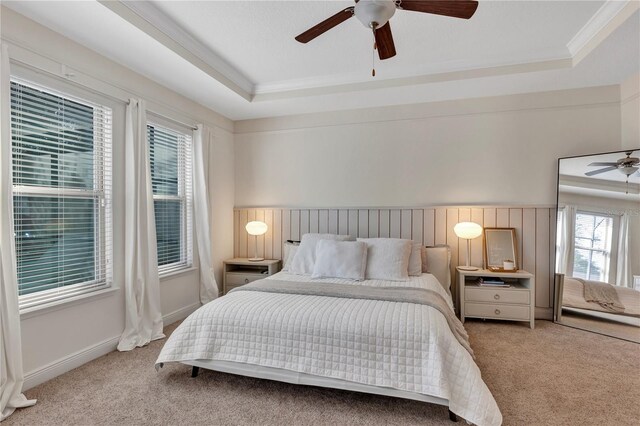 bedroom featuring light carpet, ceiling fan, a raised ceiling, and baseboards