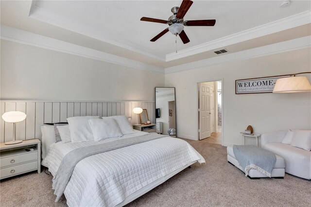 bedroom with ornamental molding, a raised ceiling, and light colored carpet