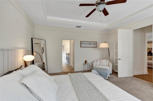 bedroom with ornamental molding, a raised ceiling, visible vents, and ceiling fan