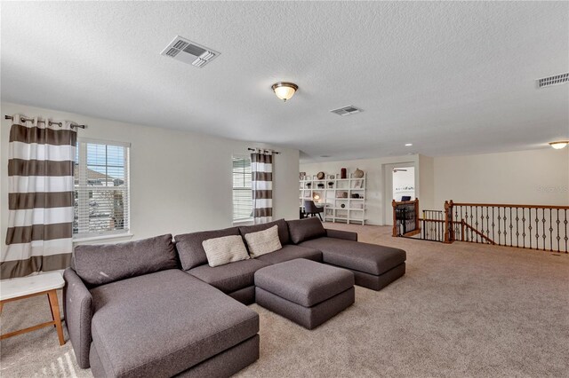 living area featuring visible vents, a textured ceiling, and light colored carpet