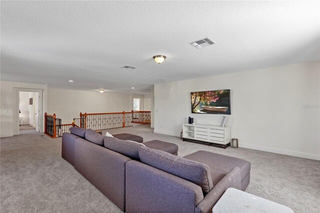 living area featuring baseboards, visible vents, light carpet, and a textured ceiling