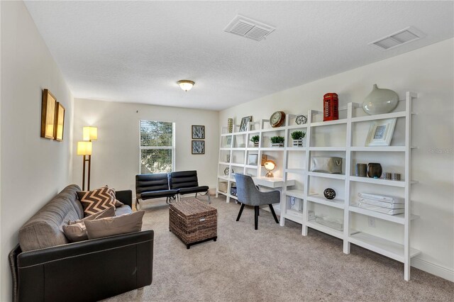 living area featuring light carpet, a textured ceiling, and visible vents