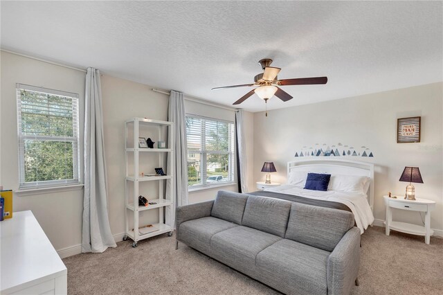 bedroom with light carpet, a ceiling fan, baseboards, and a textured ceiling