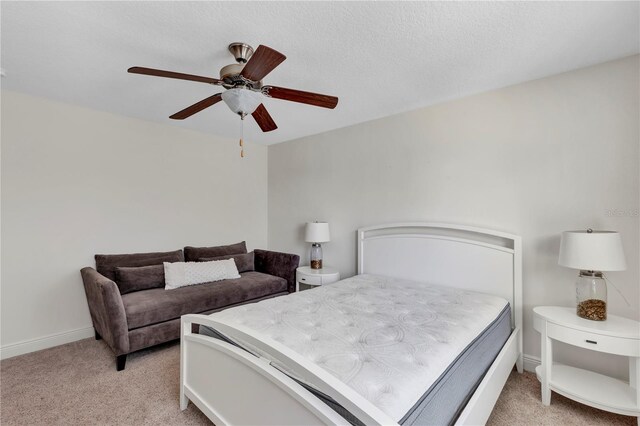 bedroom with baseboards, ceiling fan, a textured ceiling, and light colored carpet