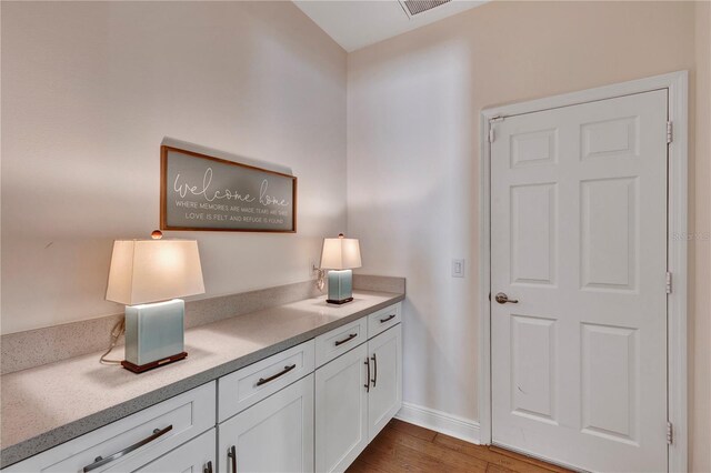 interior space featuring visible vents, baseboards, and dark wood-type flooring