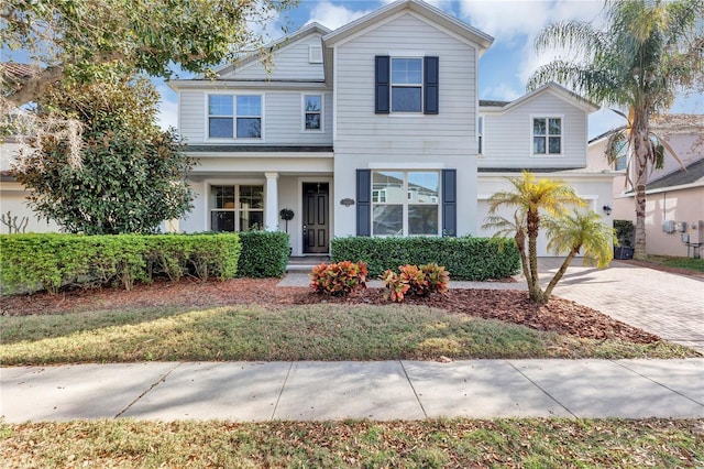 traditional-style home featuring an attached garage and decorative driveway