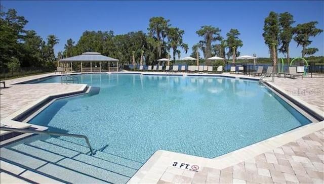 community pool featuring a patio area, fence, and a gazebo