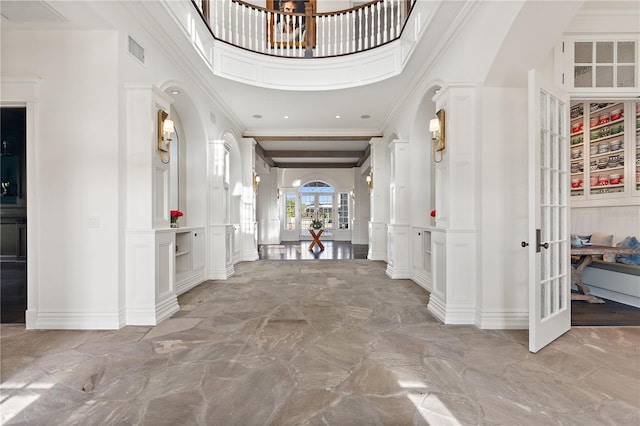foyer with a towering ceiling, french doors, and beamed ceiling