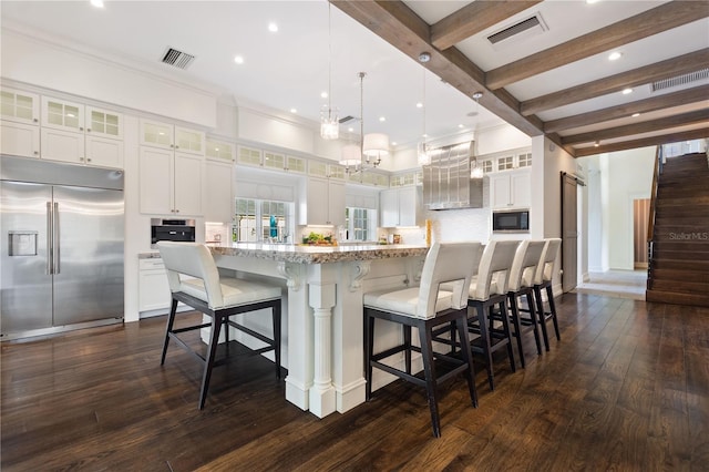kitchen featuring built in appliances, decorative light fixtures, white cabinetry, light stone counters, and tasteful backsplash